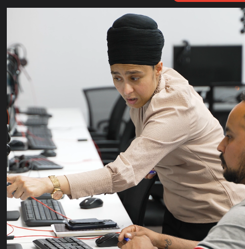 Rupinder Kaur coaching a student one-to-one at a workstation in the Target Language Academy classroom, Auckland